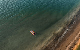 an aerial view of a small boat floating in the ocean