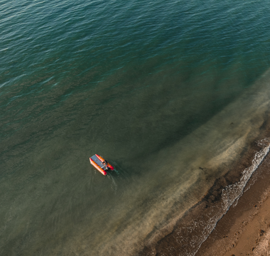 an aerial view of a small boat floating in the ocean