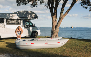 a person is standing next to a camper van and an inflatable raft
