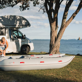 a person is standing next to a camper van and an inflatable raft