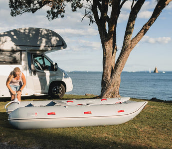 a person is standing next to a camper van and an inflatable raft