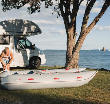a person is standing next to a camper van and an inflatable raft